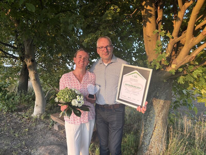 Heiko und Eva mit dem Pokal, der Urkunde und einem Blumenstrauß zur Verleihung des Landessieger Gästeliebling 2026